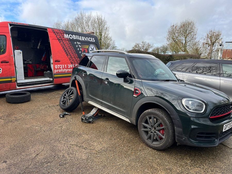 Tyre being changed on a dark Mini with the van's equipment open