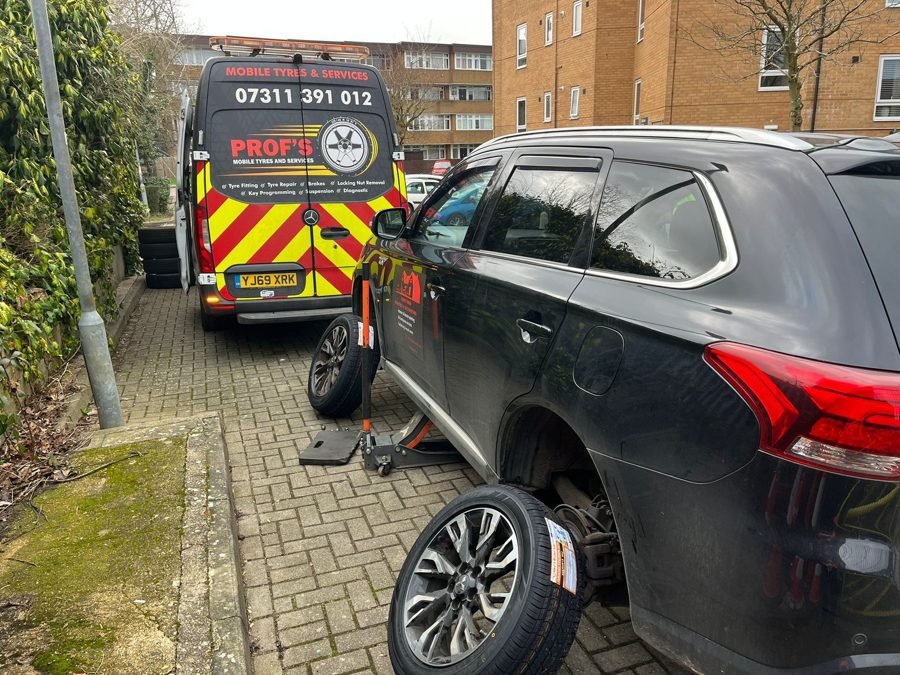 Wheel off a dark SUV at the kerb, van parked behind