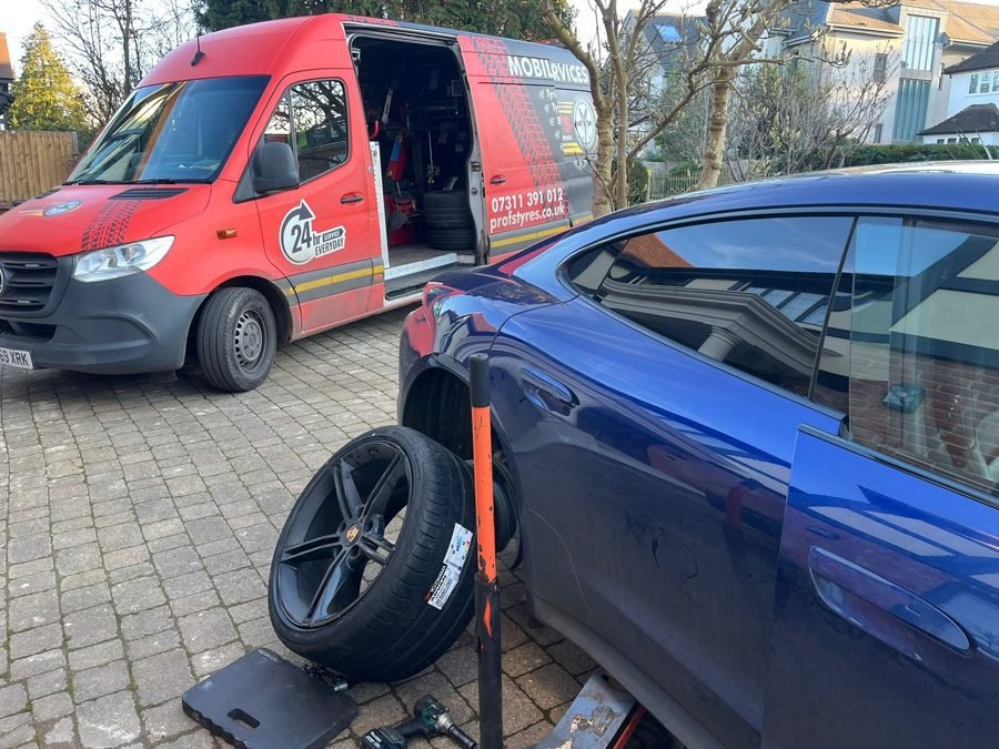 Tyre fitting on a blue car on a driveway