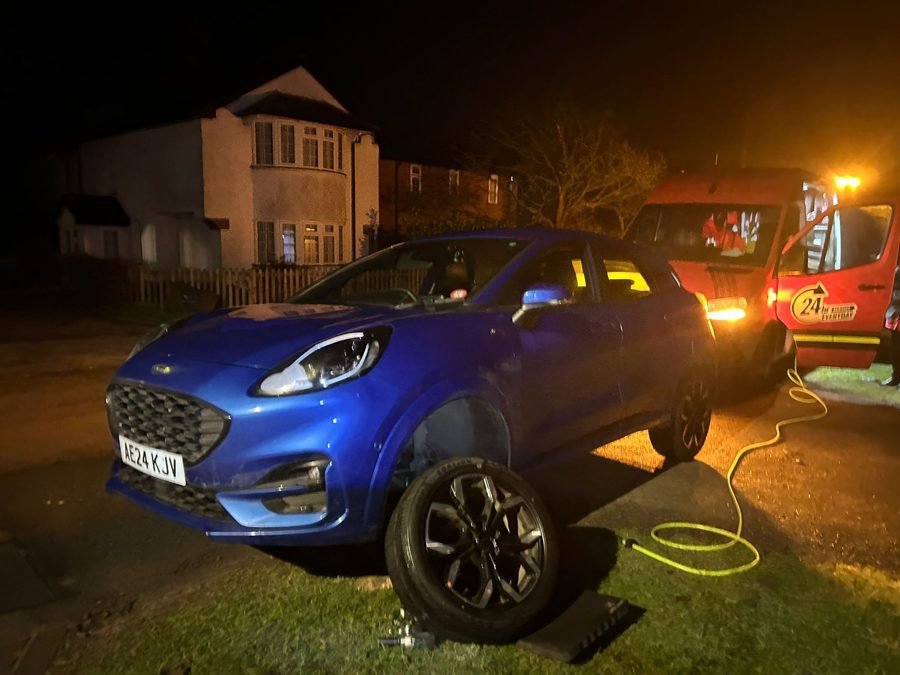 Night-time tyre change on a blue Ford, van lights flashing behind